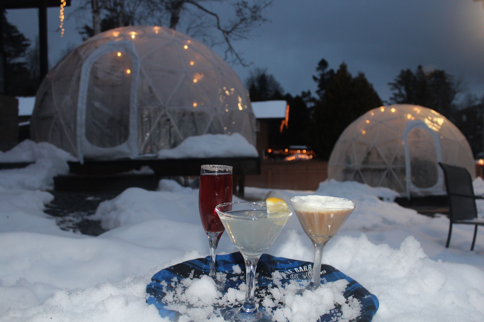Two martini glasses are sitting on a tray in the snow.