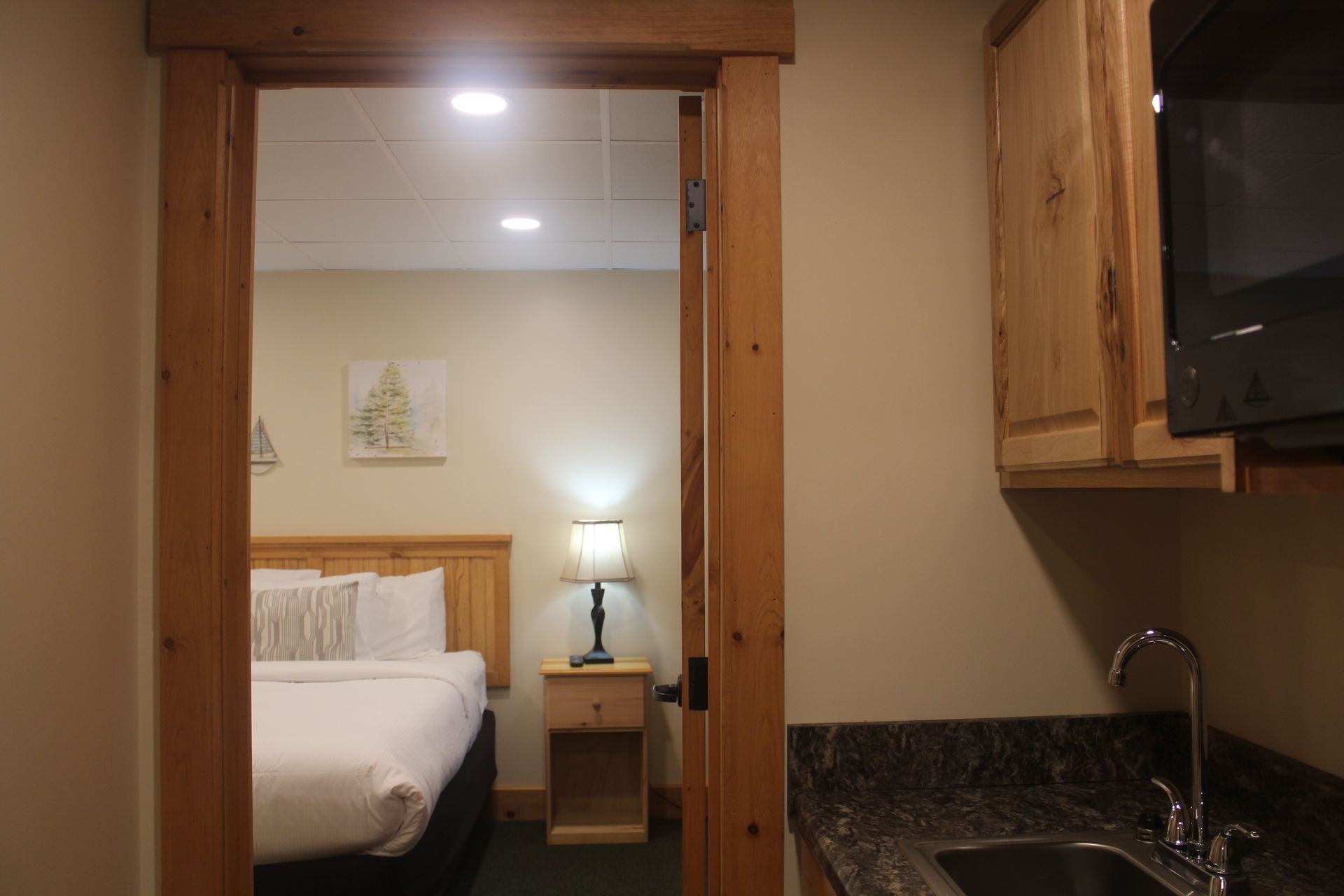 A hotel room with a bed , sink and microwave.
