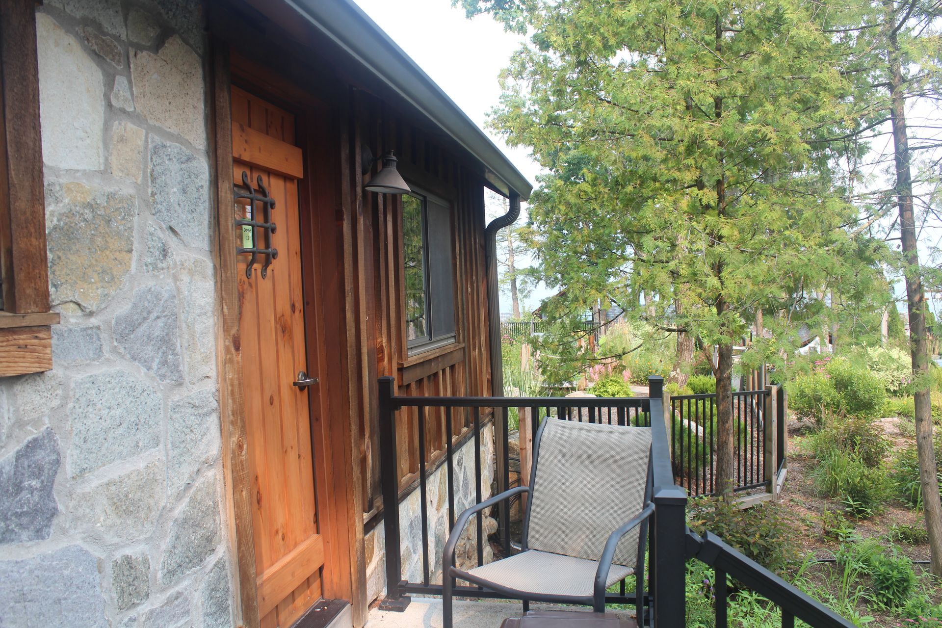 A stone house with a wooden door and a chair on the porch