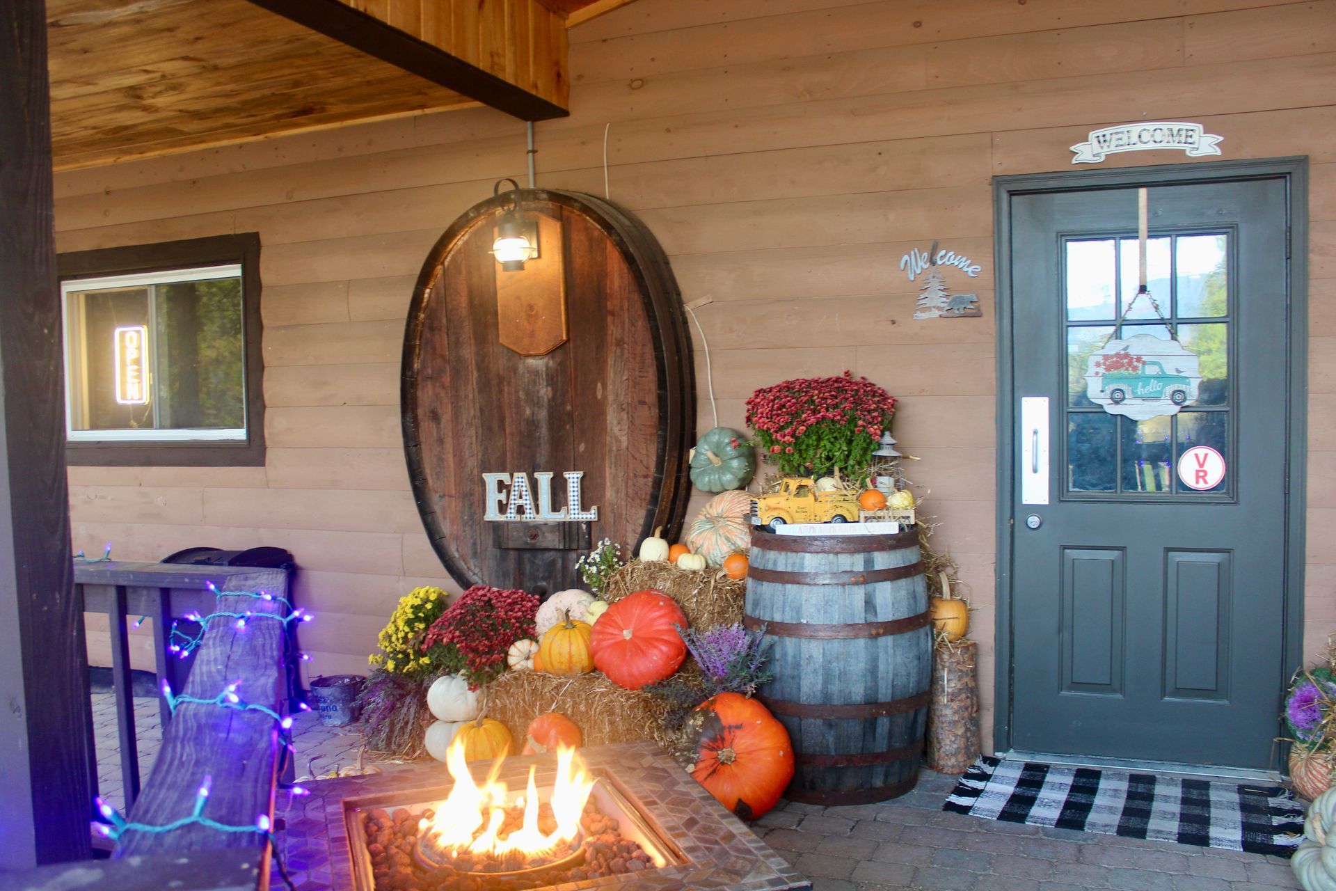 There is a fire pit in front of a building with a sign that says fall.