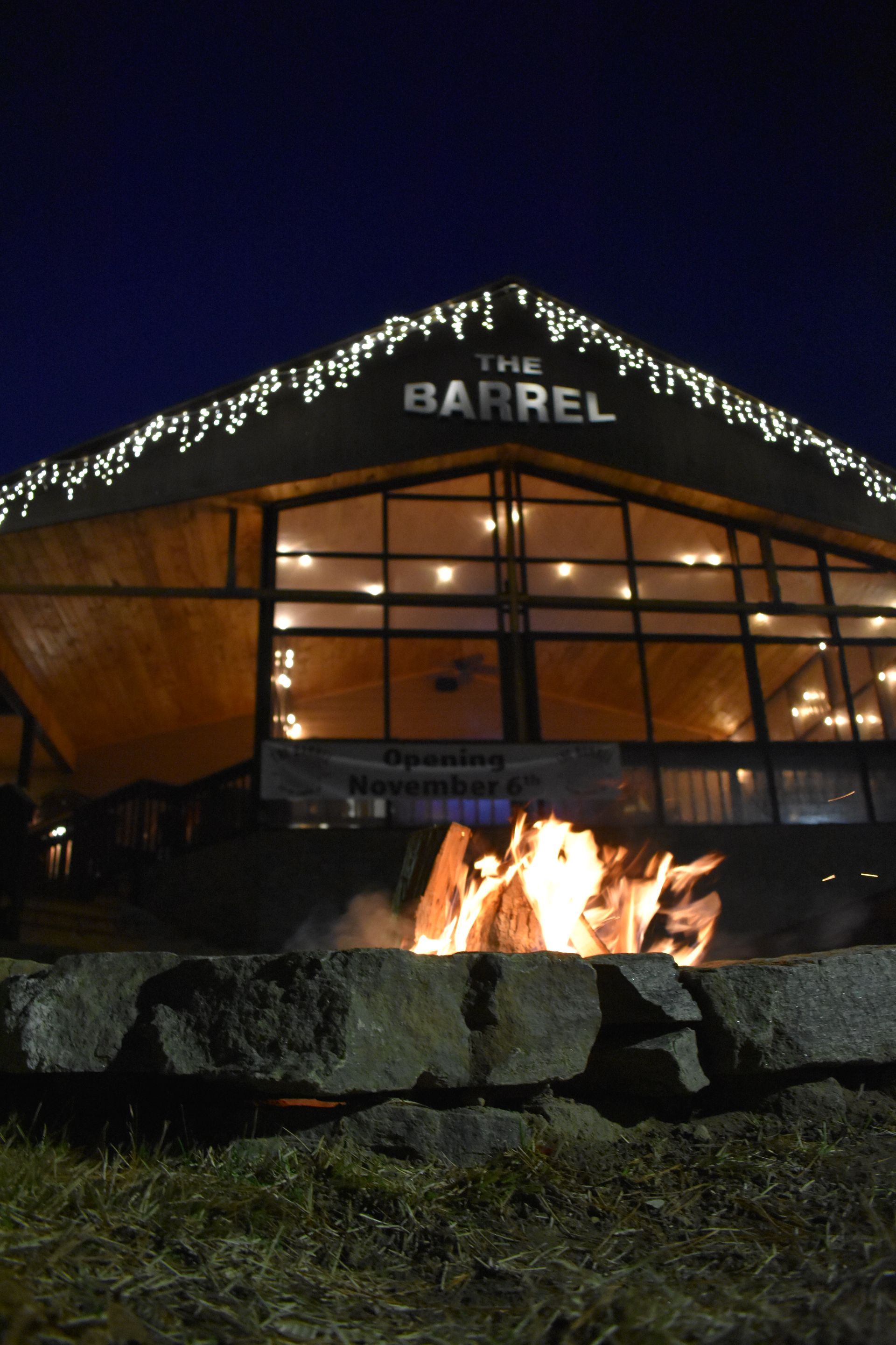 A large building with a fire pit in front of it called the barrel