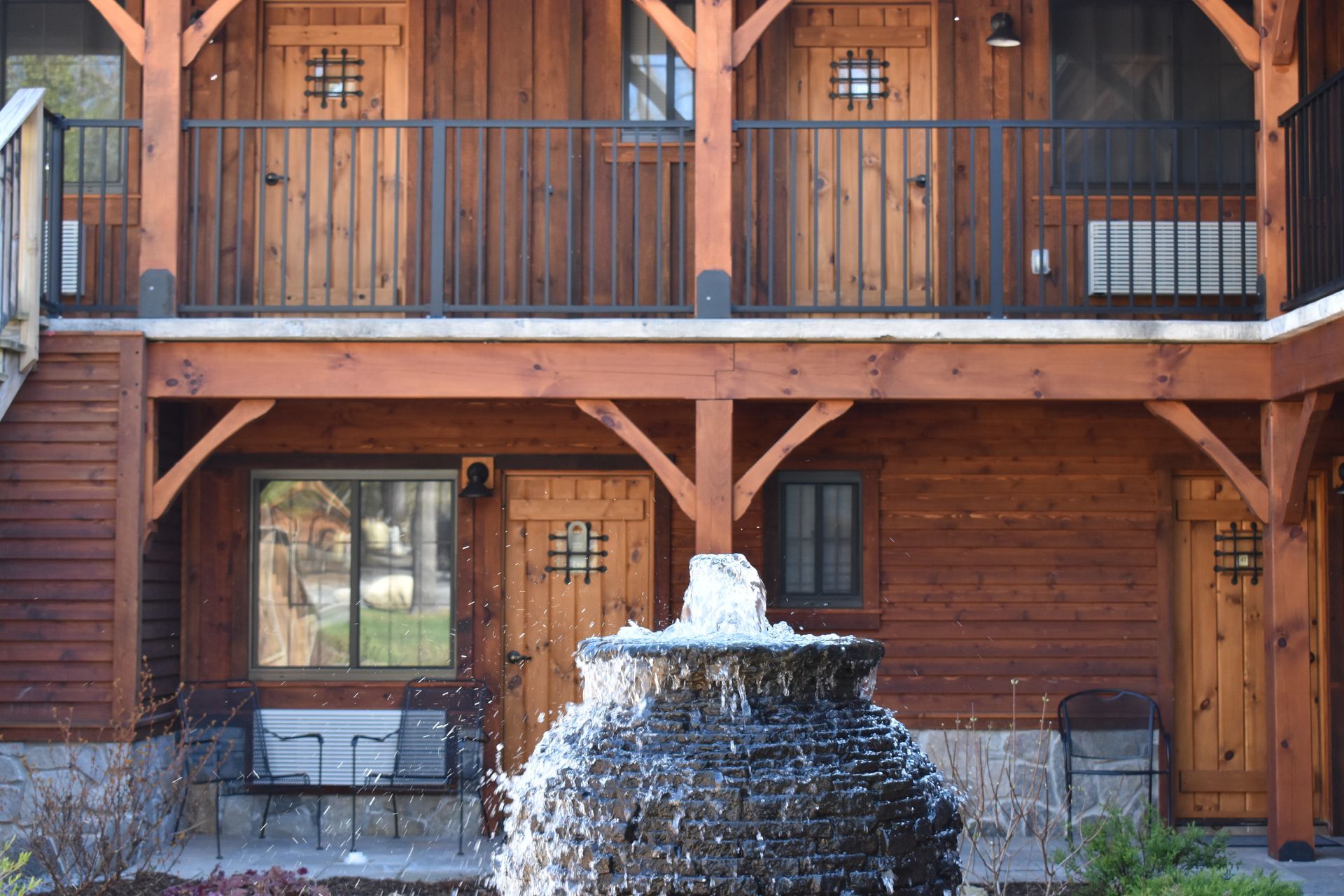 A wooden house with a fountain in front of it