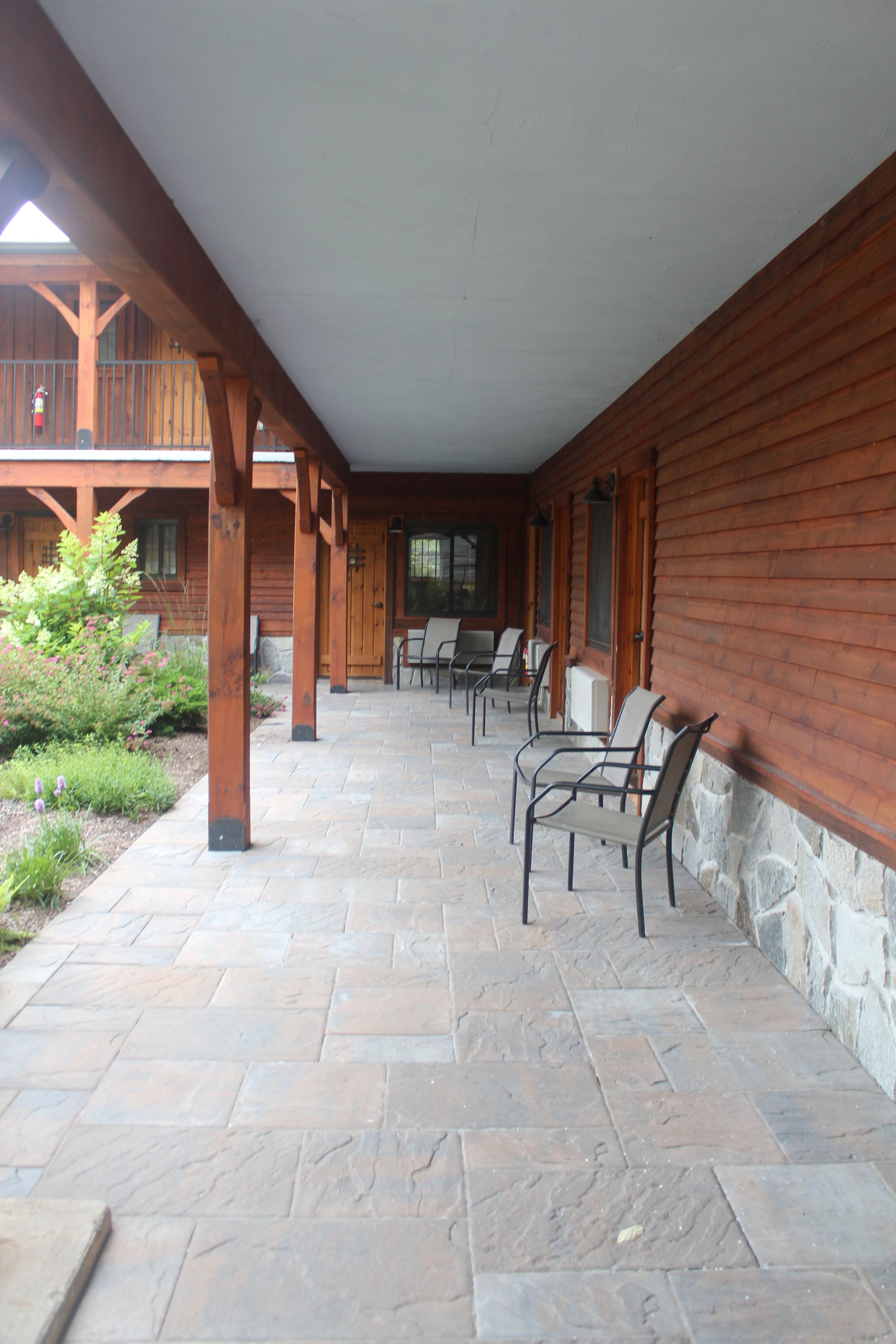 A long hallway with chairs and tables in front of a wooden building