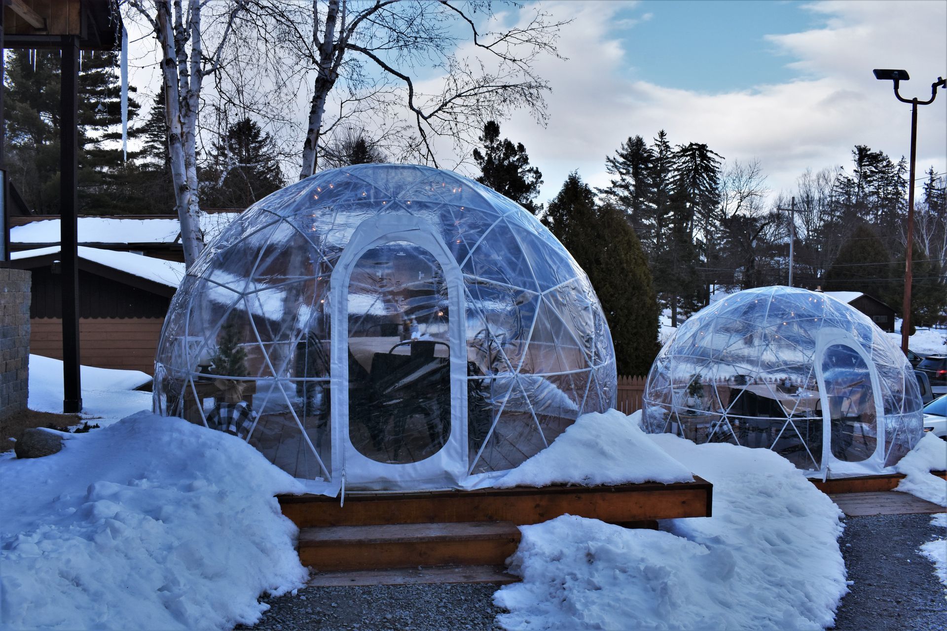 Two clear igloos are sitting in the snow.