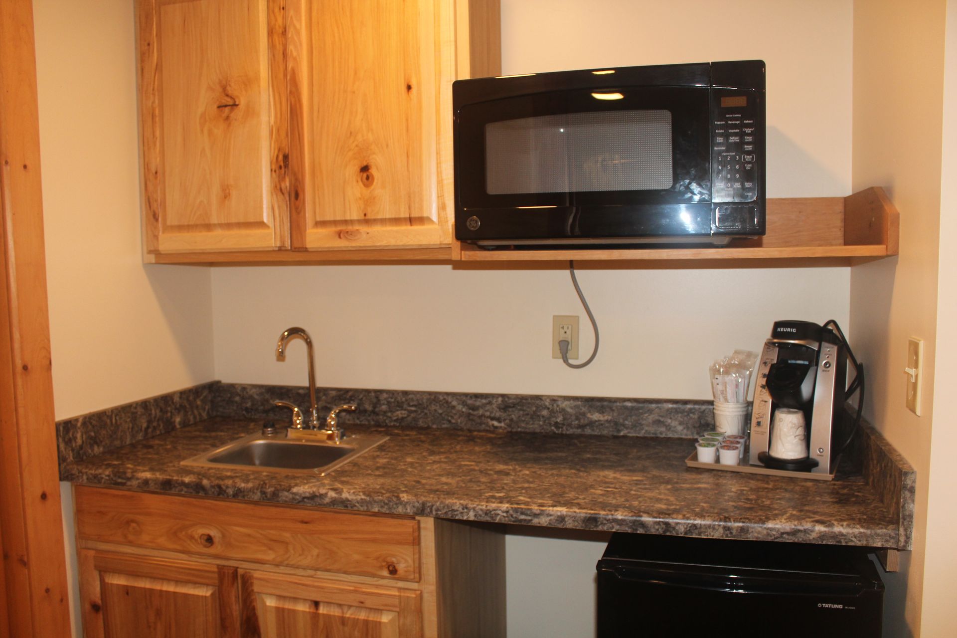 A kitchen with a sink a microwave and a coffee maker