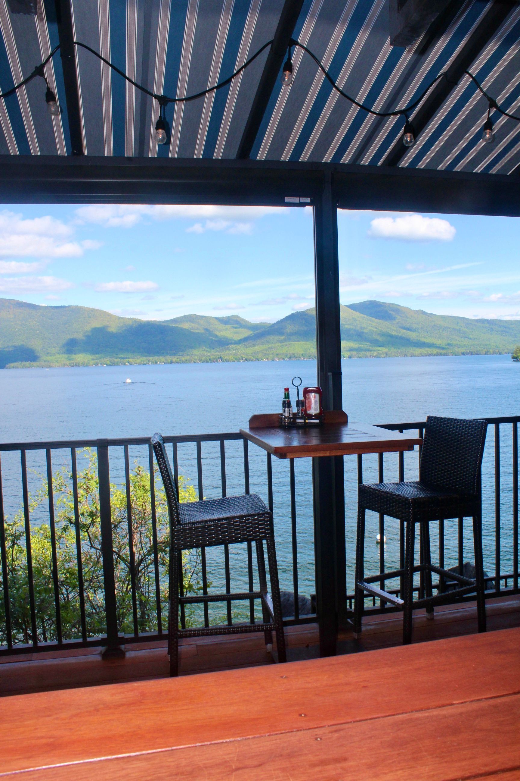 A table and chairs on a balcony overlooking a lake