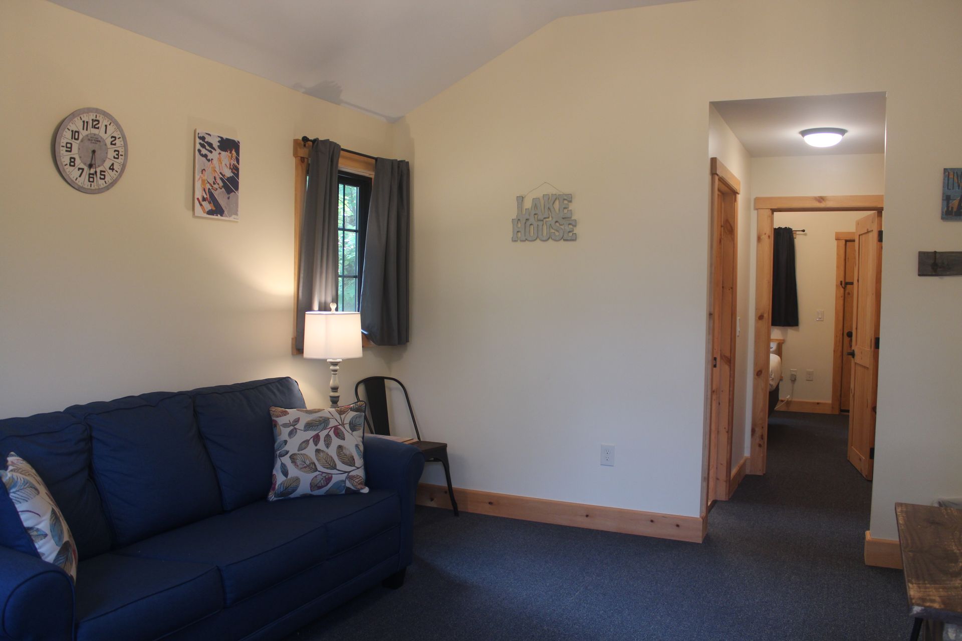 A living room with a blue couch and a clock on the wall