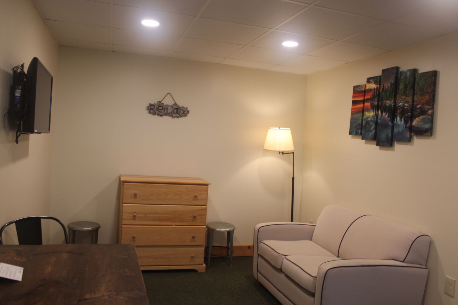 A living room with a couch , dresser , lamp and television.