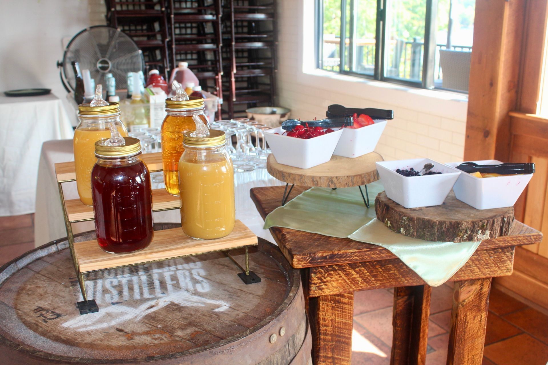 A table with jars of honey and bowls of fruit on it.
