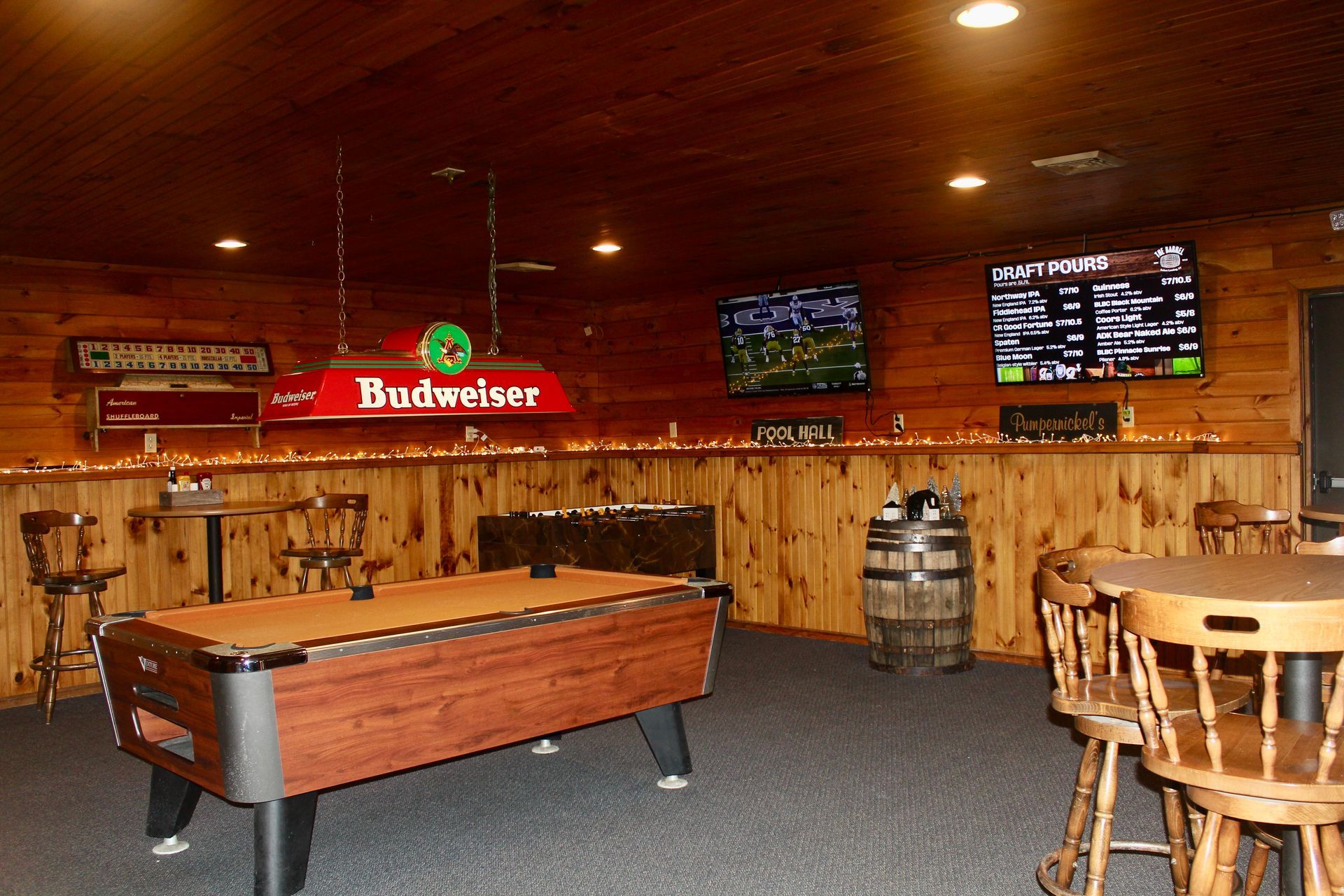 A pool table in a bar with a budweiser light above it