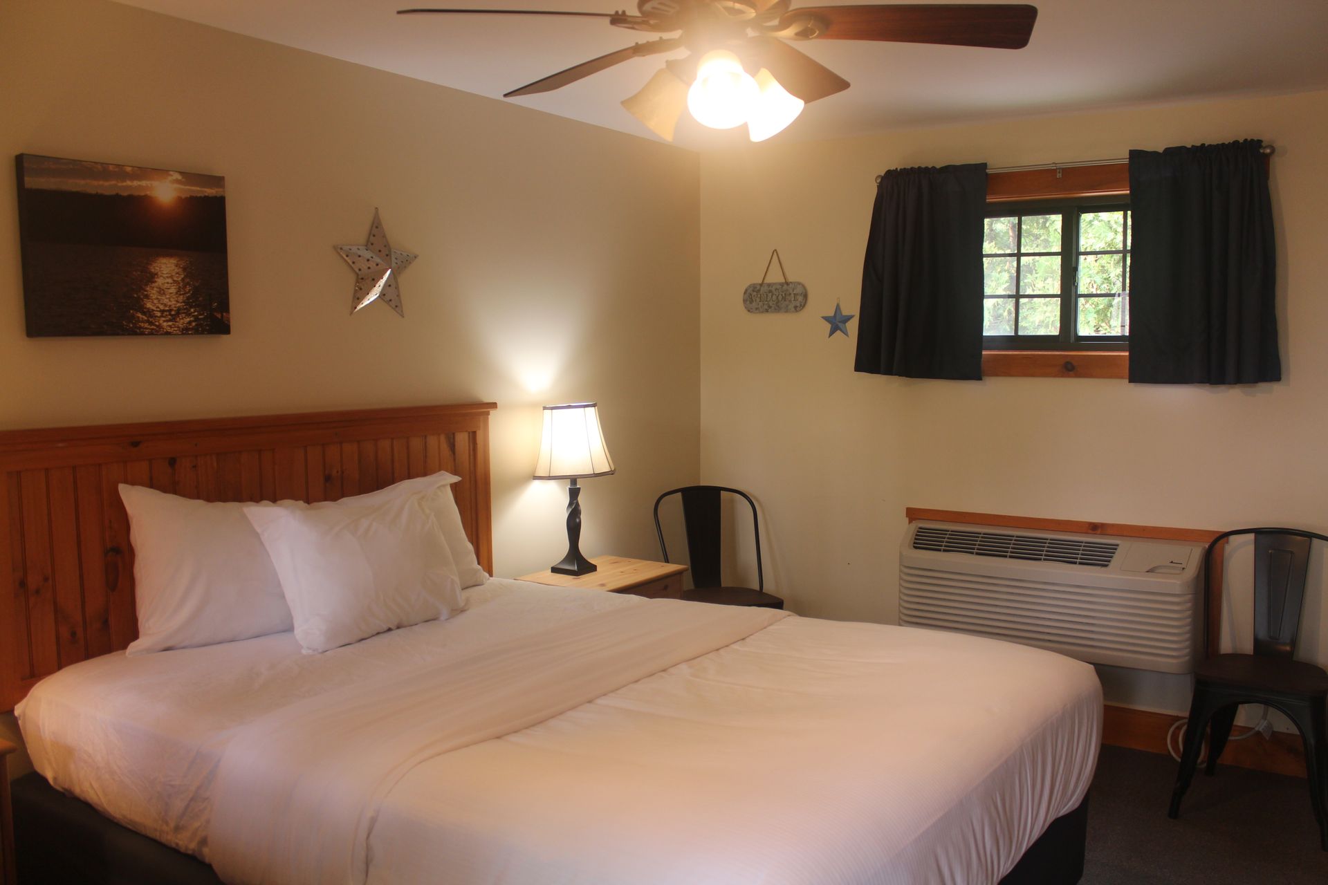 A hotel room with a king size bed and a ceiling fan