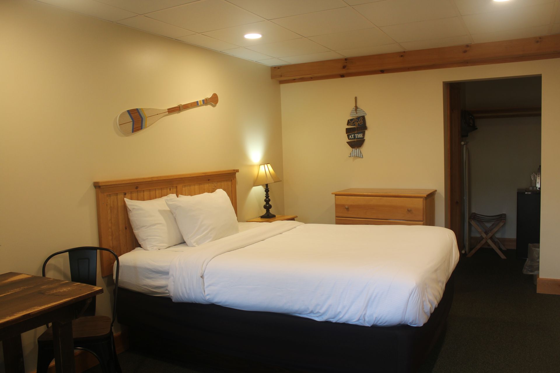 A hotel room with a king size bed , dresser , table and chairs.