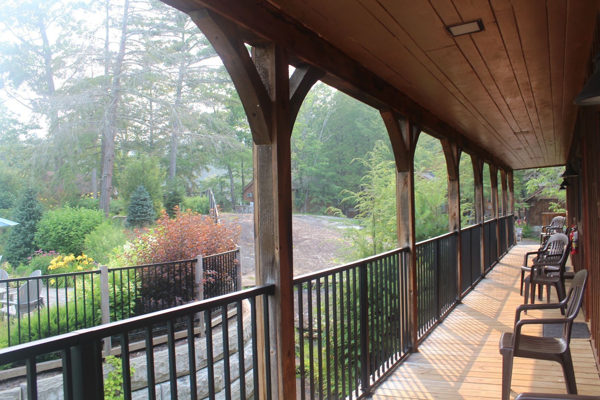A long wooden porch with a black railing and chairs