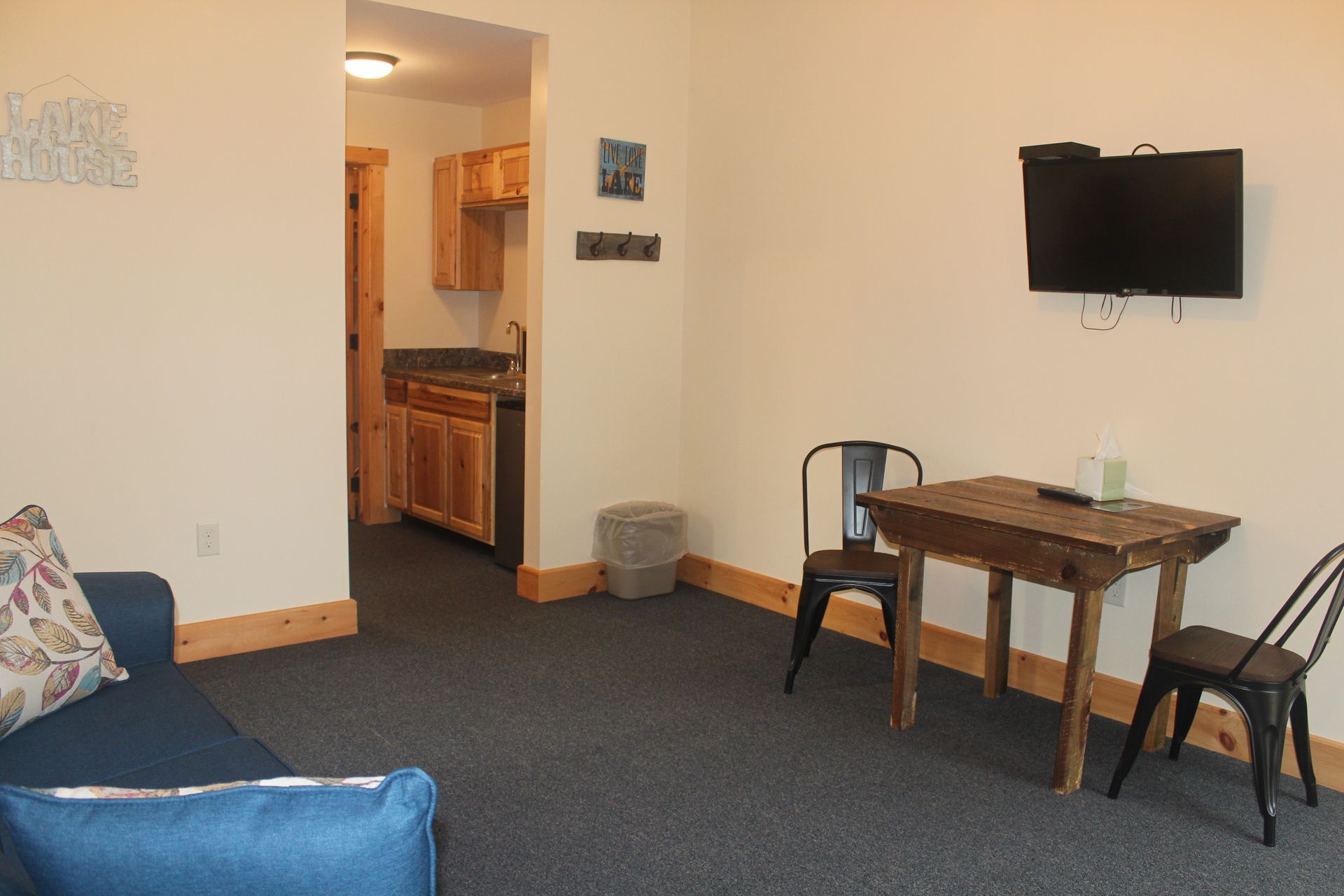 A living room with a couch , table , chairs and a flat screen tv.