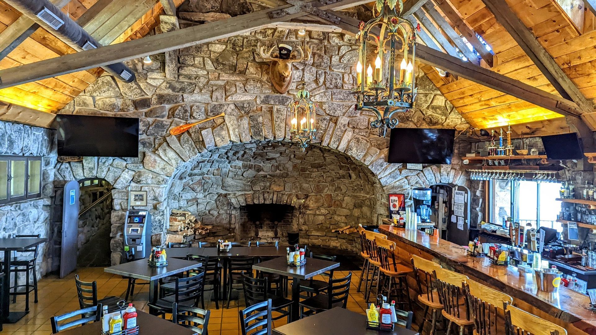The inside of a restaurant with tables and chairs and a fireplace.