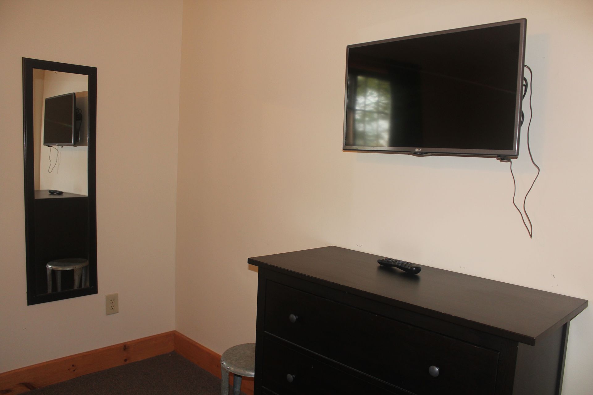 A bedroom with a dresser a television and a mirror