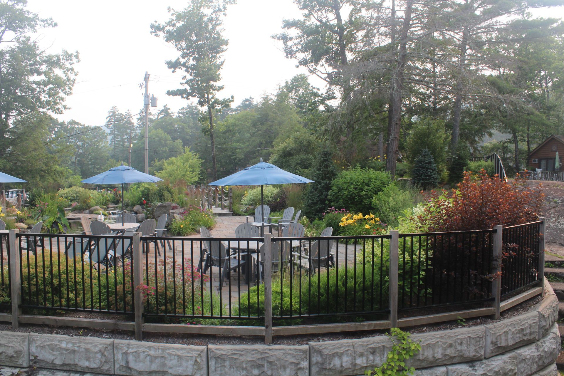 A fenced in area with tables and chairs and blue umbrellas