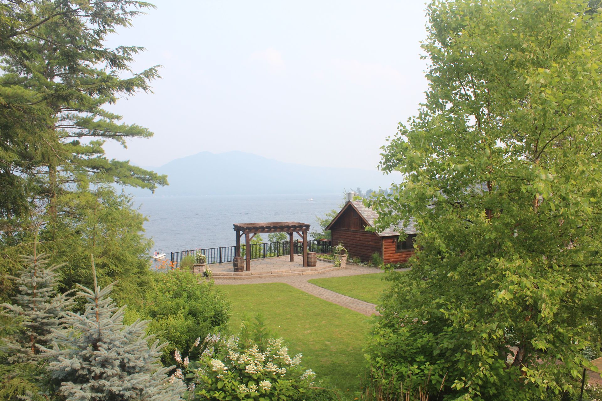 A house is surrounded by trees on a hill overlooking a lake.