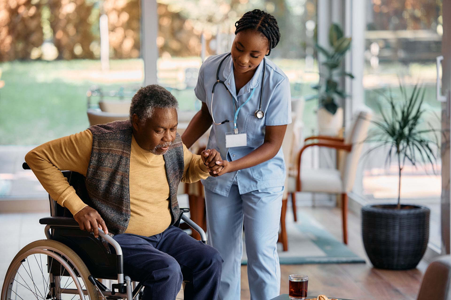 A nurse is helping an elderly man in a wheelchair.