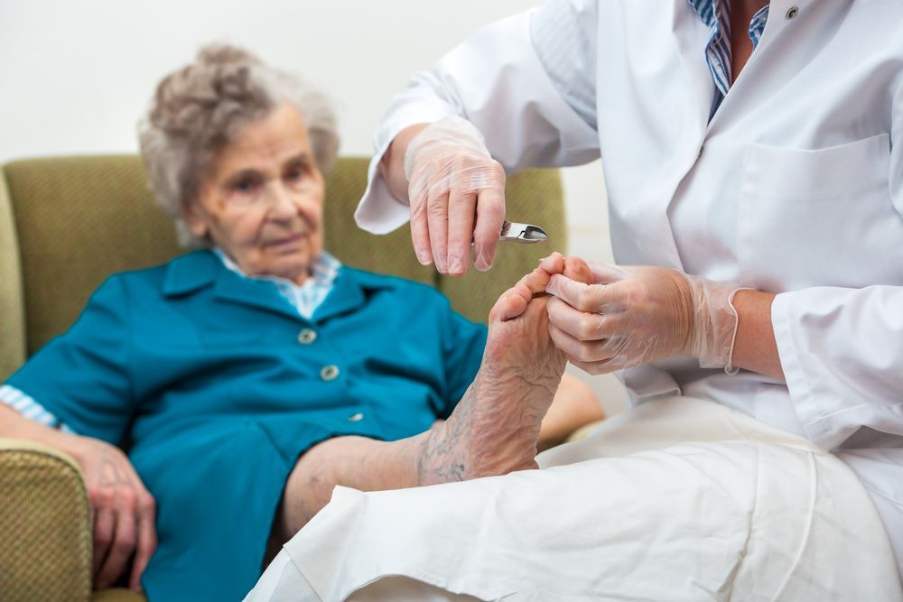 An elderly woman is getting her feet examined by a doctor.