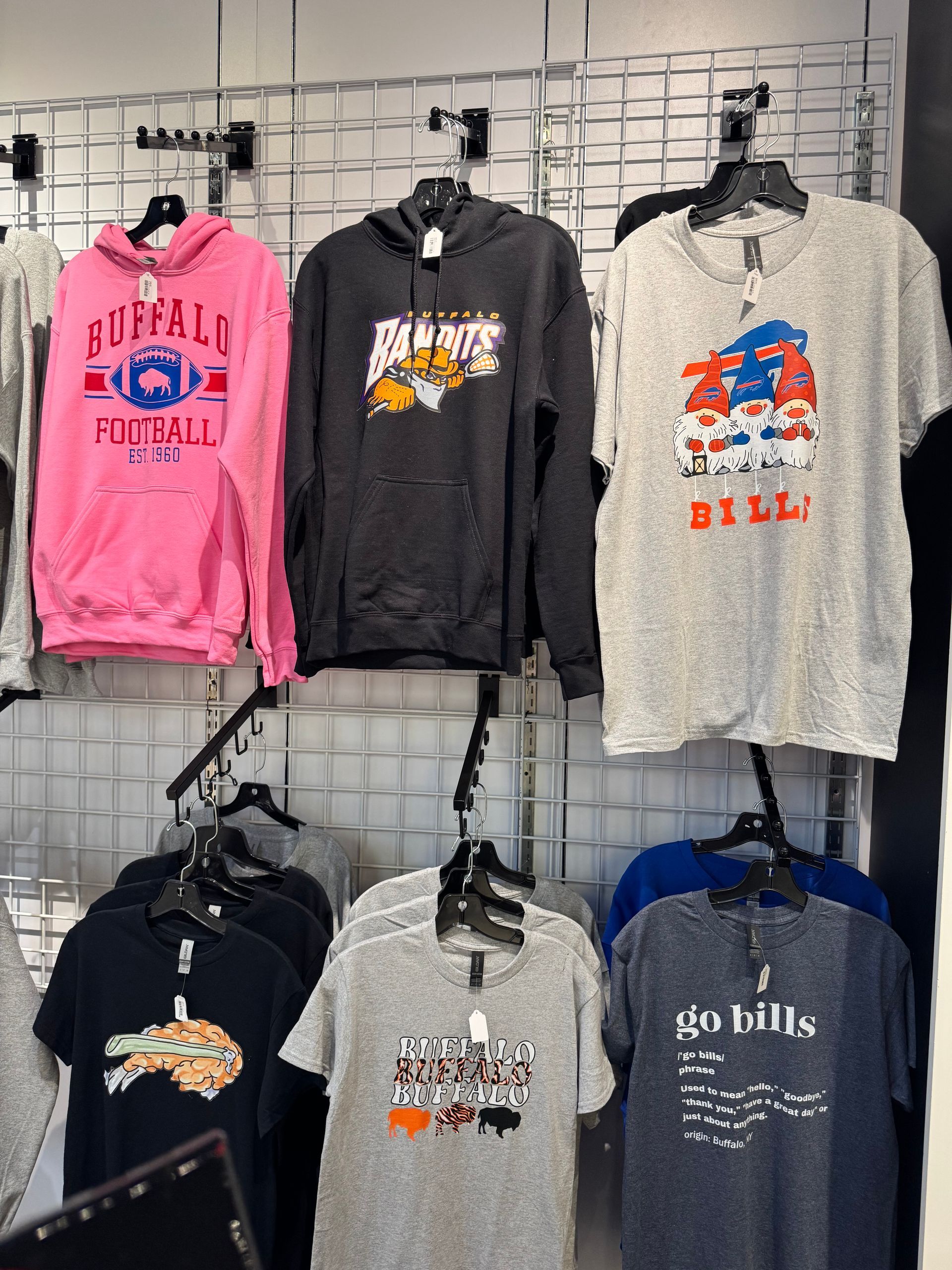 Shelves with Buffalo Bills apparel, including pink and gray hoodies, and t-shirts.