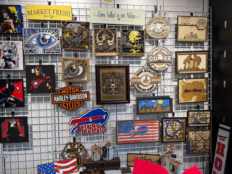 Display of various wooden art pieces on a grid, including comic book characters, logos, and cityscapes.