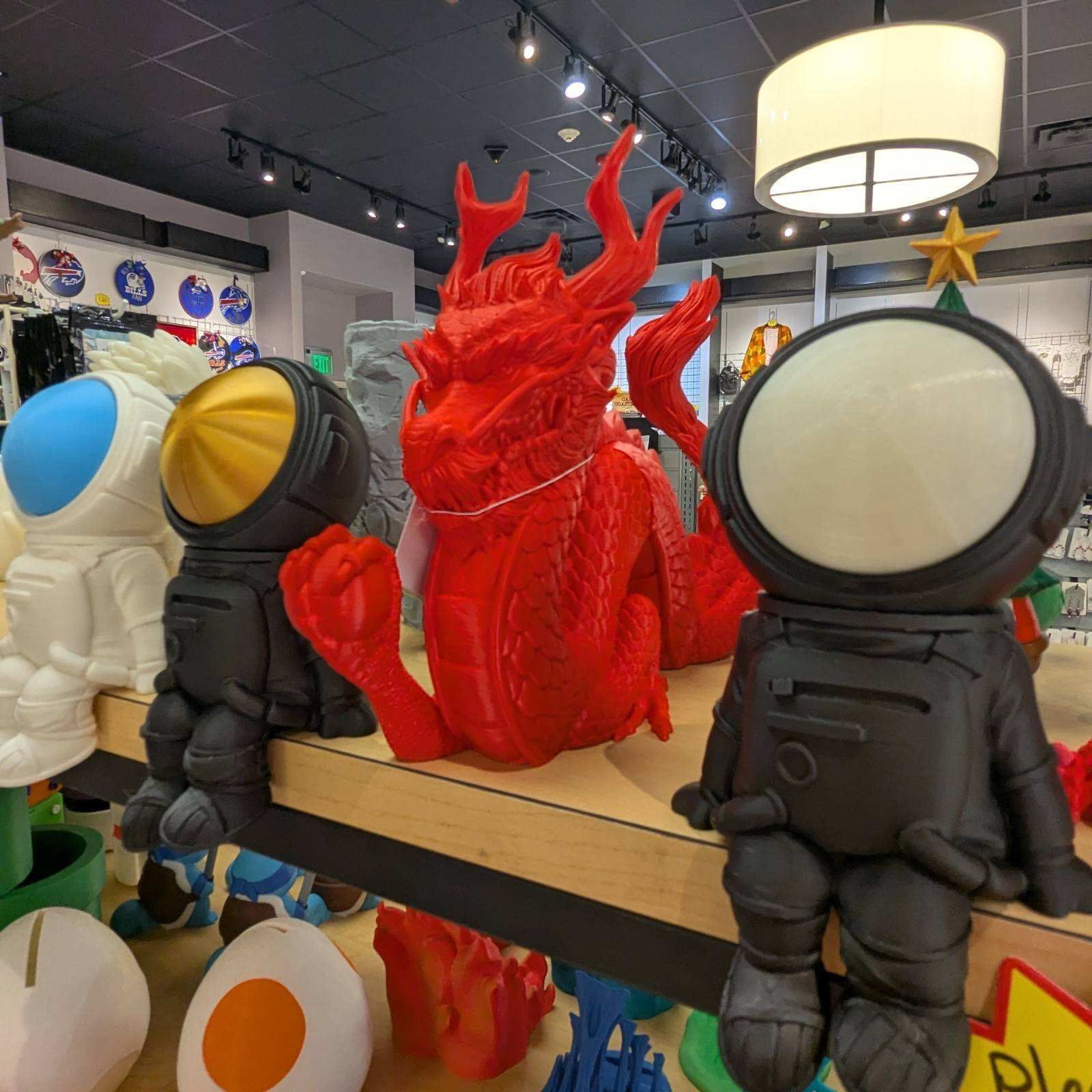 Shelf display with red dragon and astronaut figures in a store.