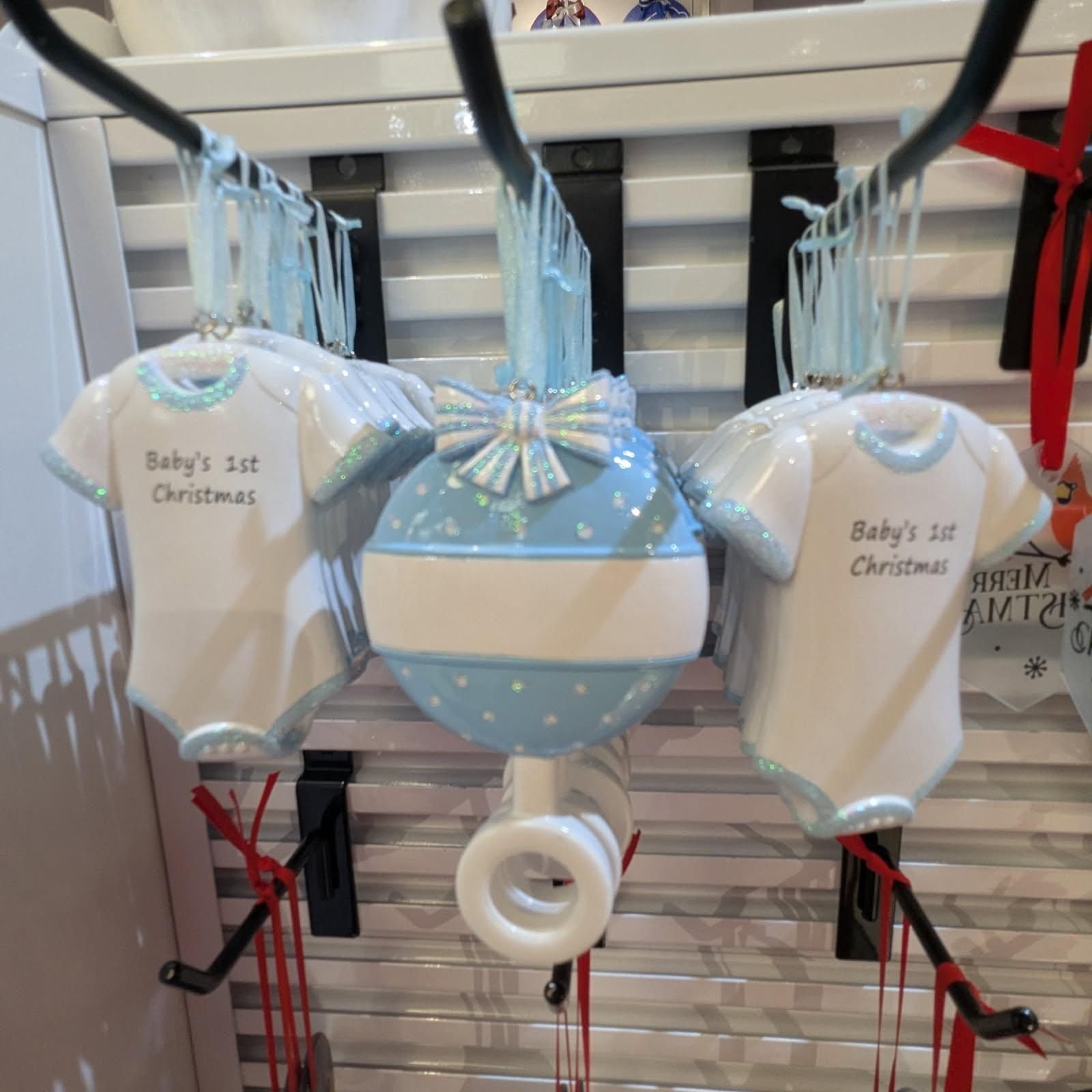 Three baby's first Christmas ornaments: two onesies and a blue patterned ball.