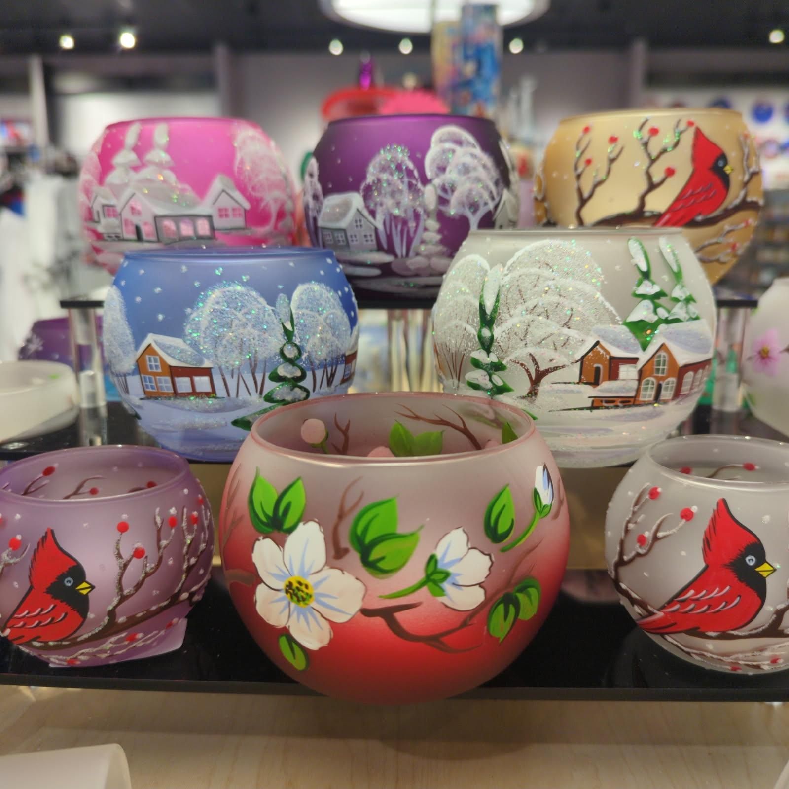 Colorful frosted glass candle holders with winter and floral scenes.