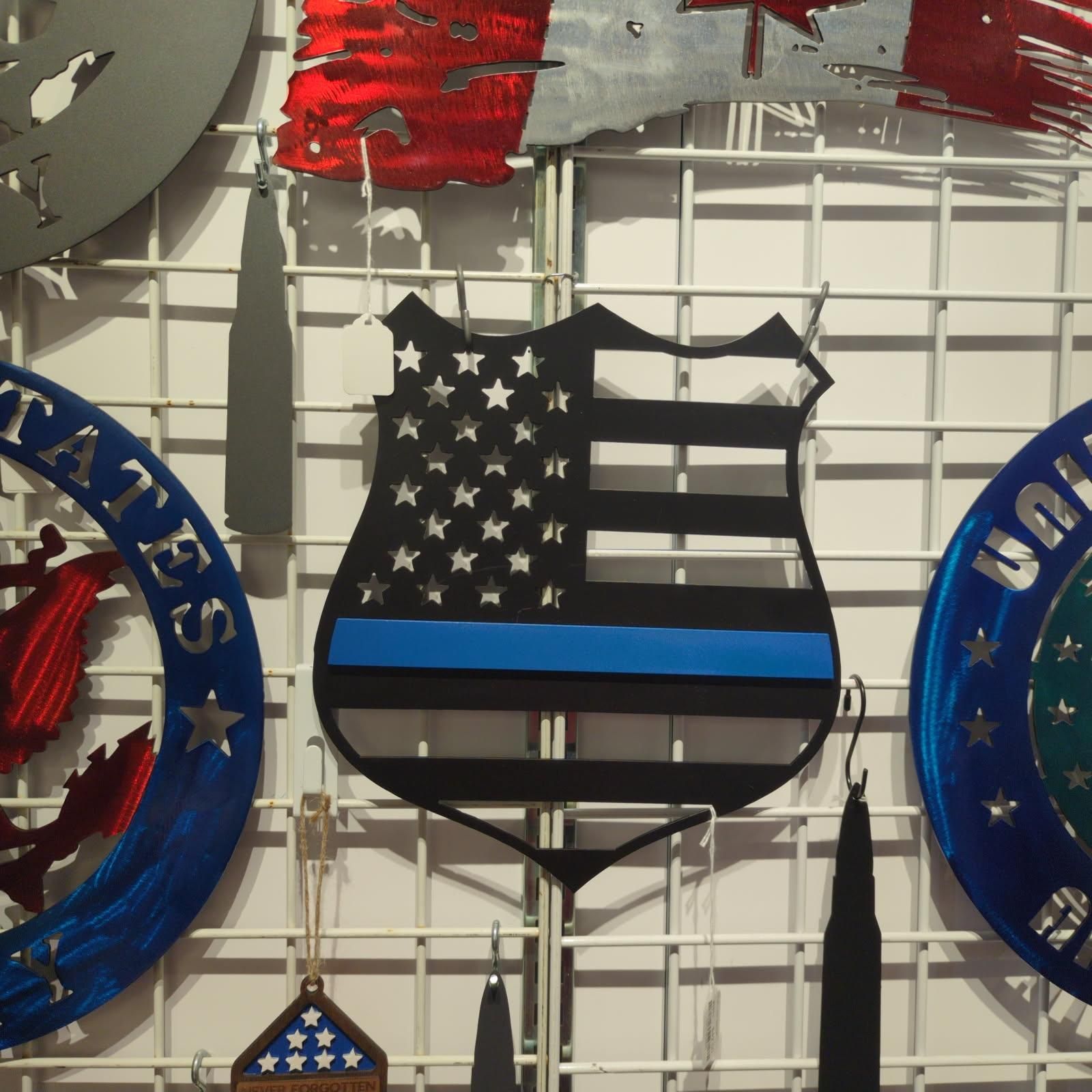 Metal art: police badge with American flag and blue line, surrounded by other patriotic metal art.