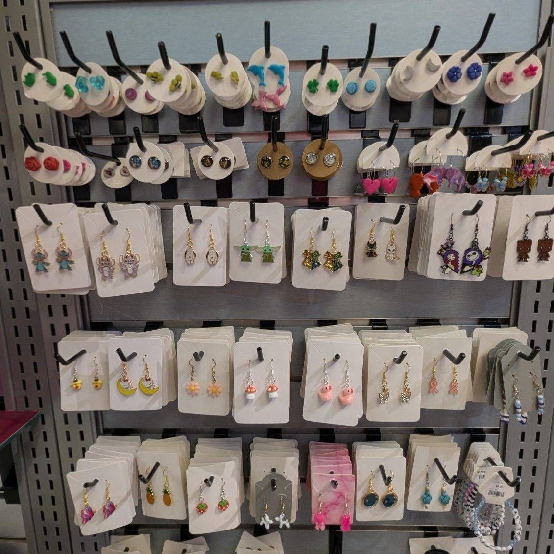 Earring display rack with multiple pairs of dangling earrings in various shapes and colors.