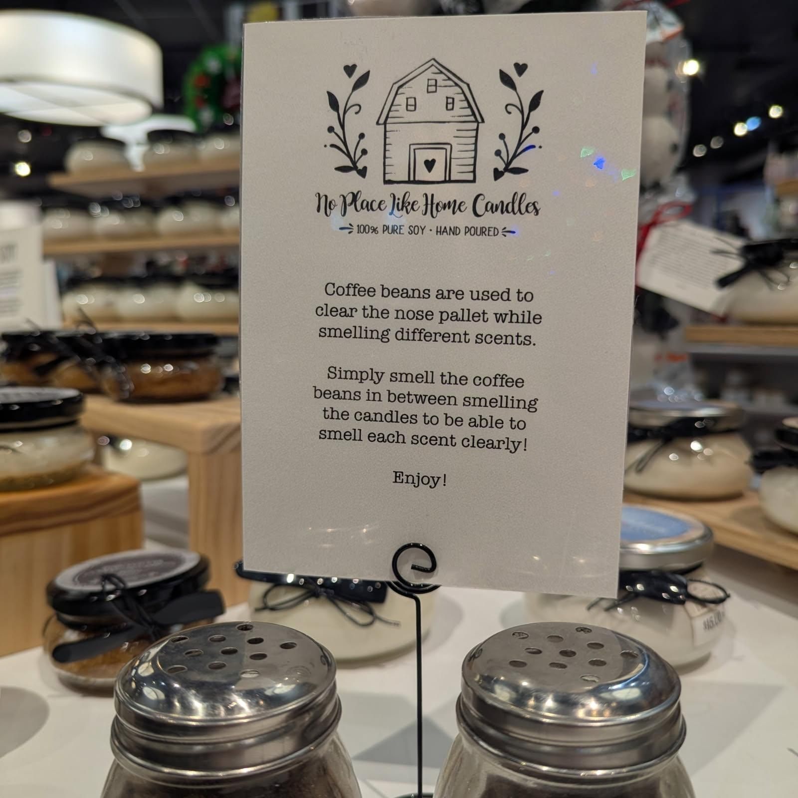 Sign with instructions for smelling candles, next to candle jars and coffee bean containers in a store.