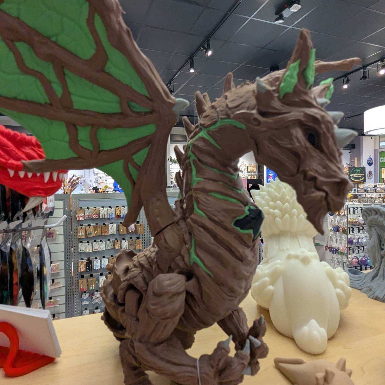 A brown, wood-textured dragon statue with green-leaf wings on display in a store.