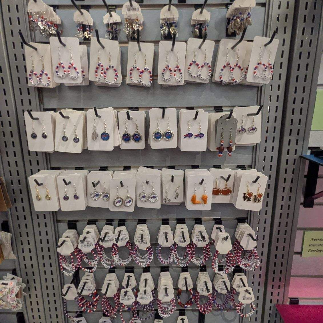 Earring display in a store, silver shelving. Rows of earrings on white cards, with various colors and styles.