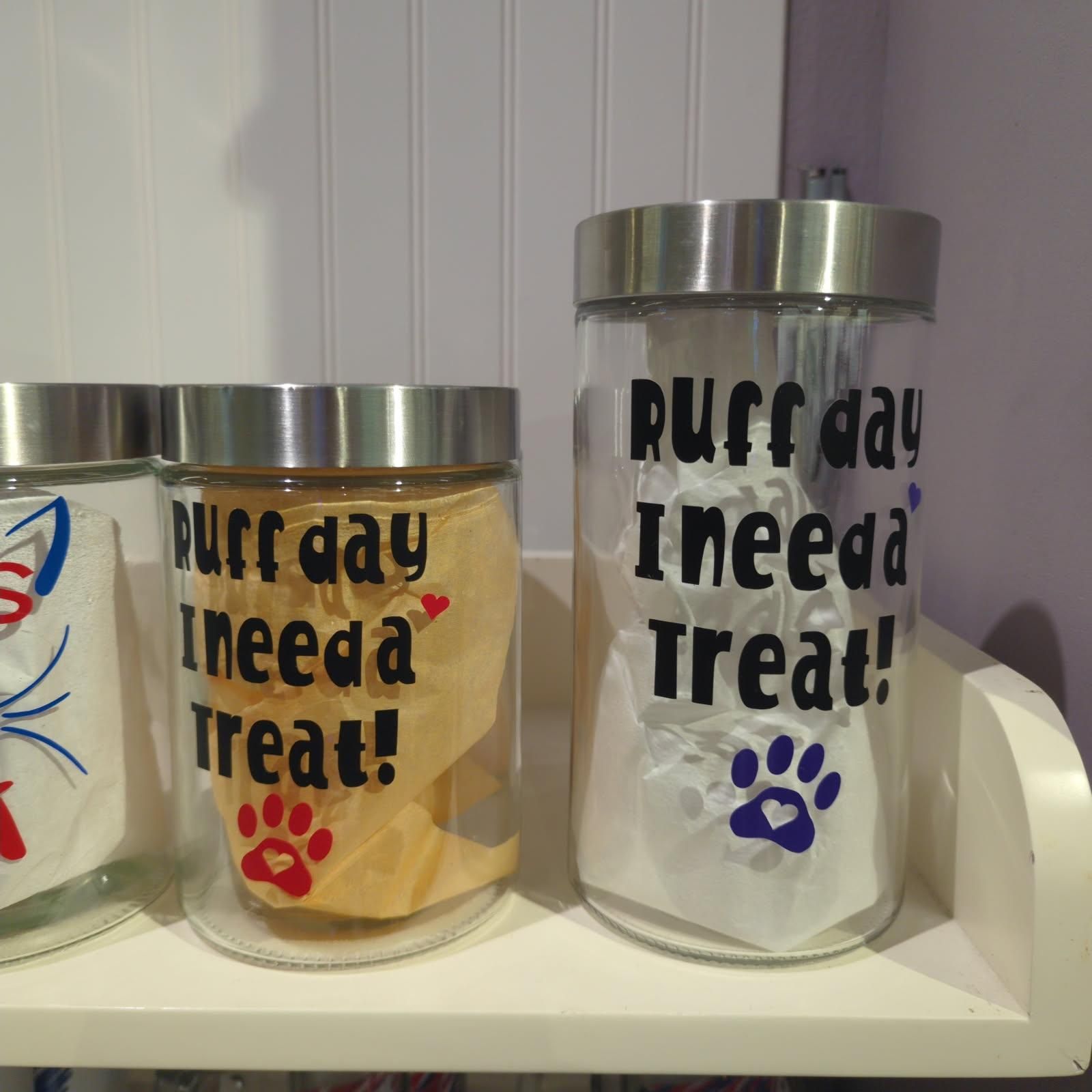 Three glass jars with silver lids on a shelf. Jars have text 
