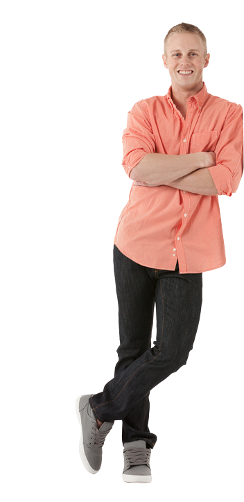 Man leans with arms crossed, wearing coral shirt, dark jeans, and grey shoes, smiling. White background.