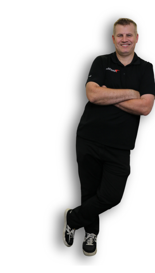 Man in black leaning against an unseen object, arms crossed, smiling.