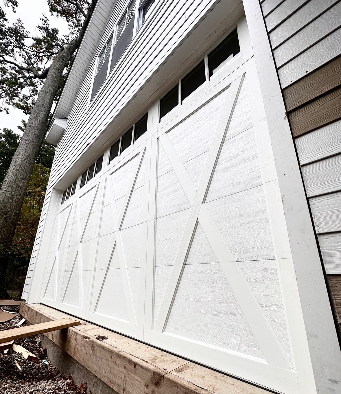 White farmhouse-style garage doors with cross-buck design on a house exterior.
