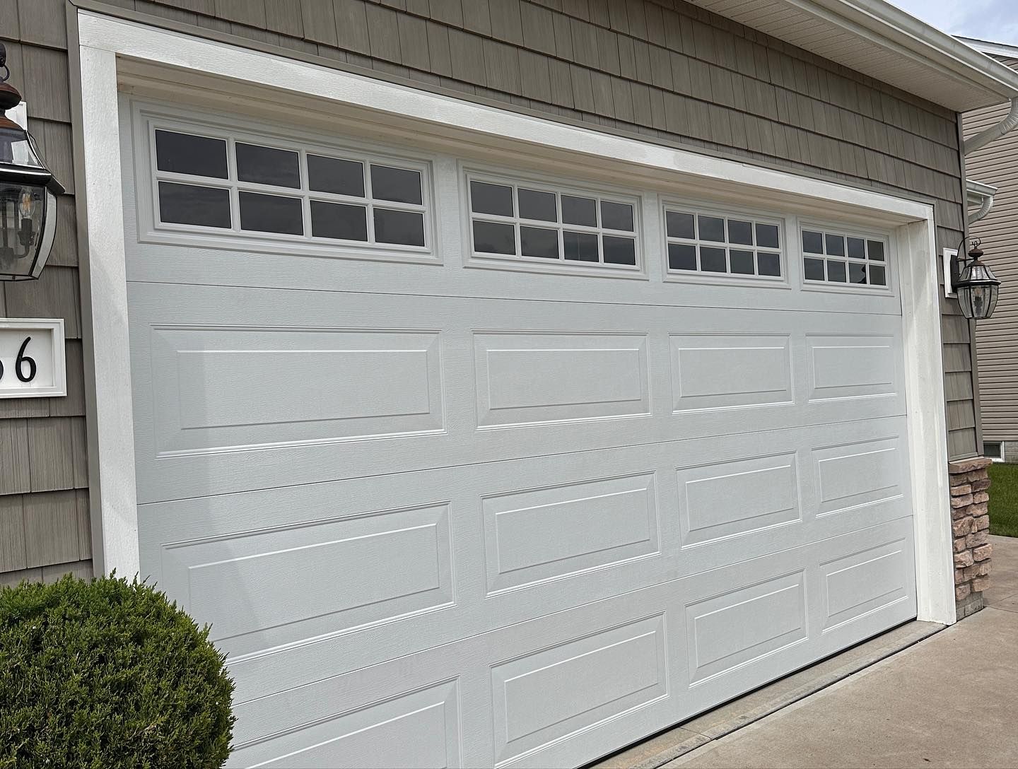 White garage door with small rectangular windows; gray siding.