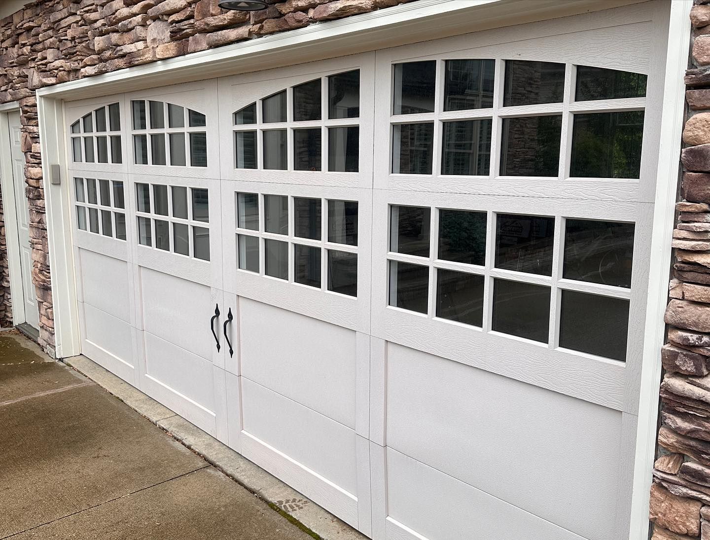 White garage door with glass panes, on a stone house exterior.