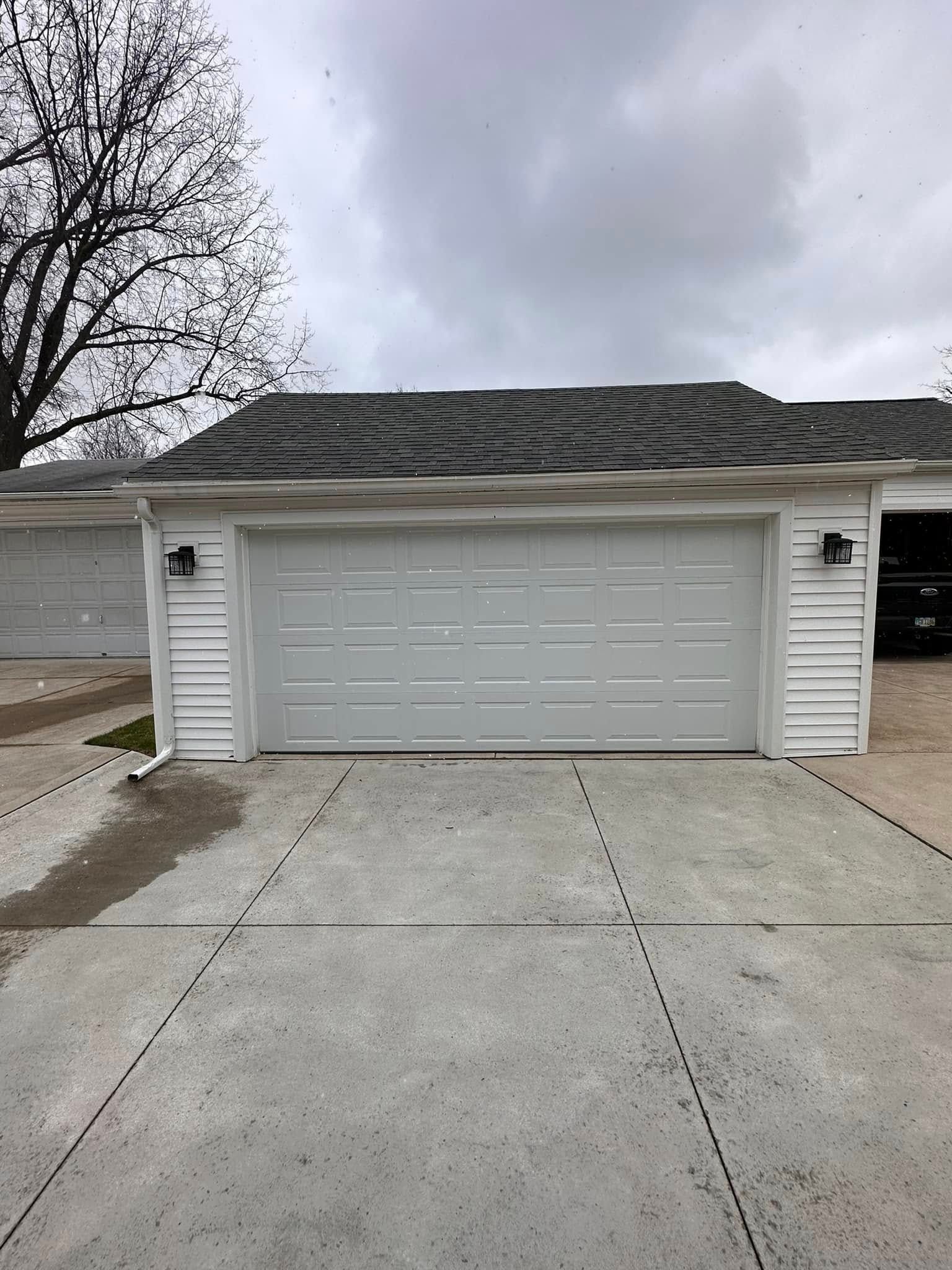 White garage with gray door and driveway under overcast sky.