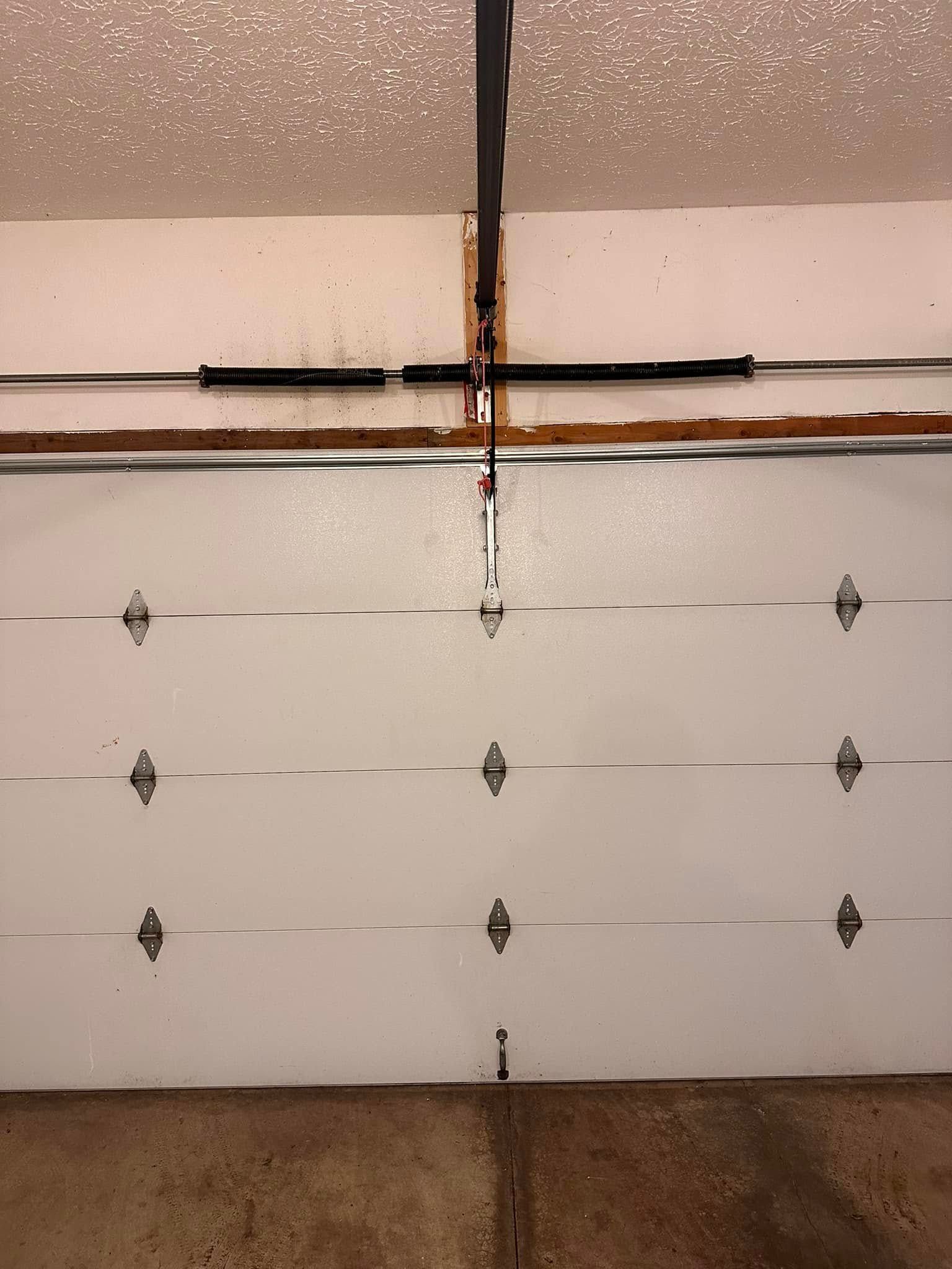 White garage door with a black overhead spring system.