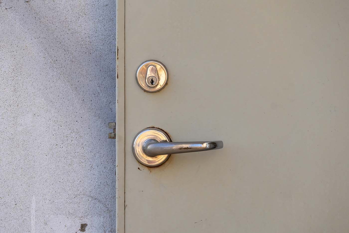 A technician repairing commercial metal door hardware in NYC building