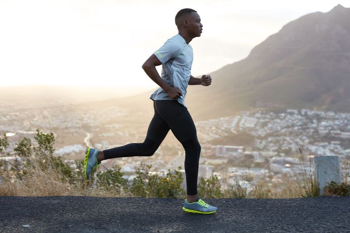 a man is running on a road with a city in the background .