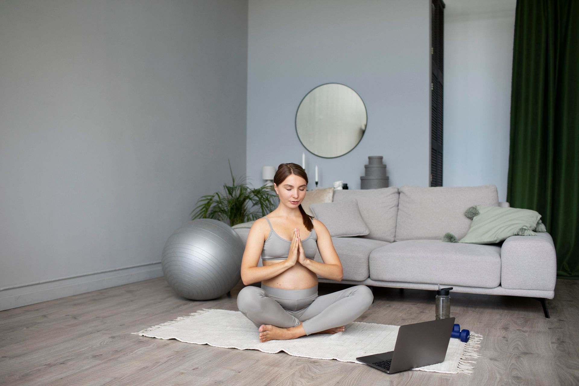 a pregnant woman is sitting on a yoga mat in a living room .
