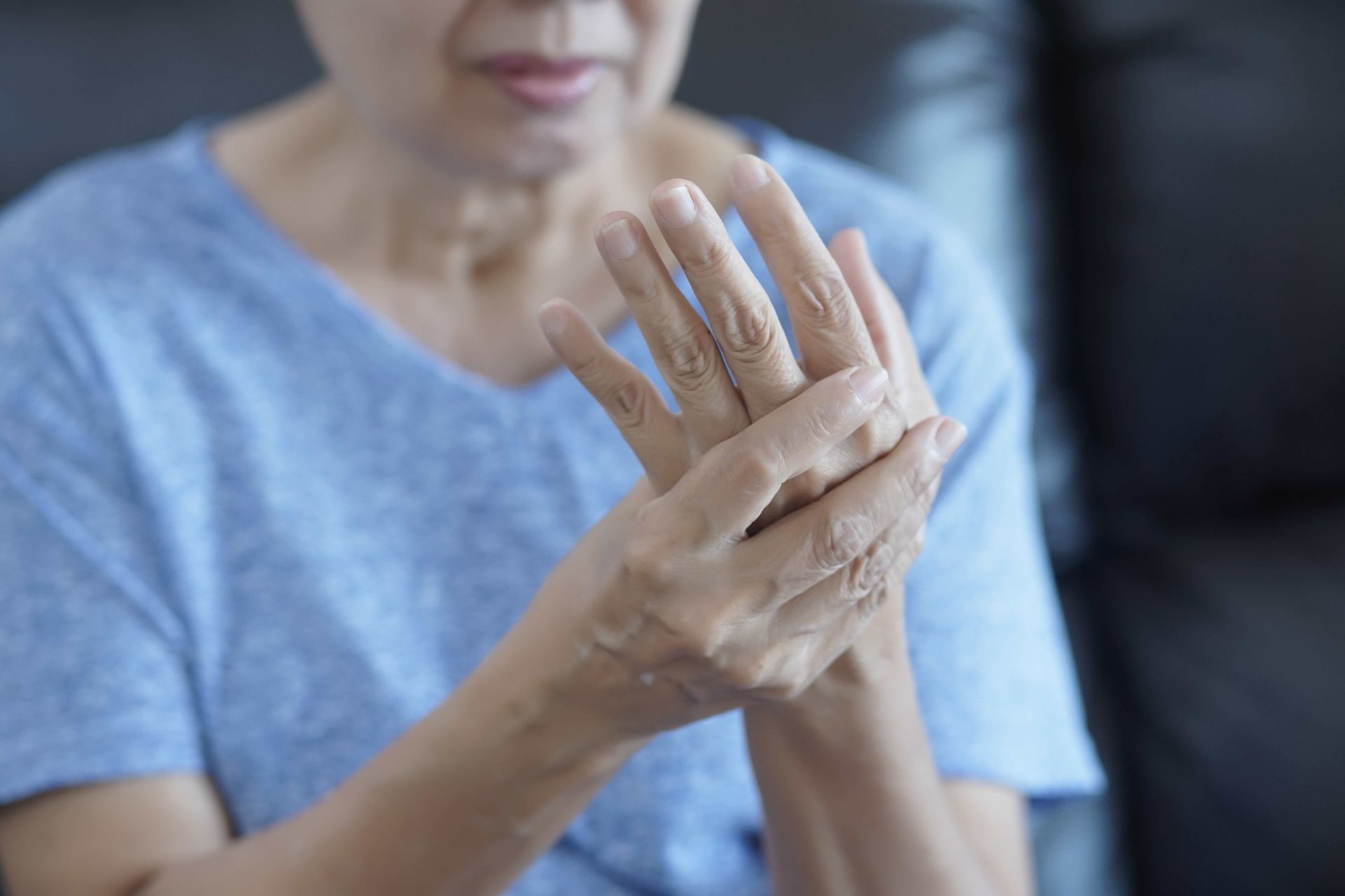 an elderly woman is holding her hand in pain .