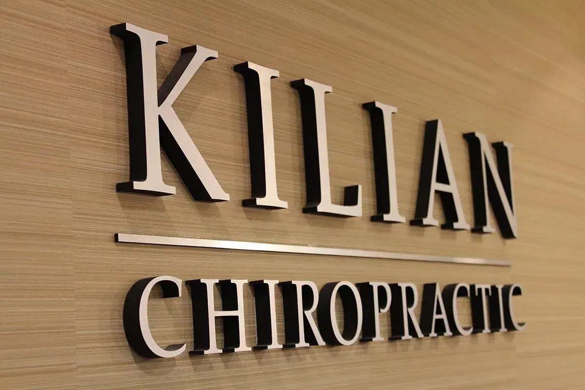 a sign for kilian chiropractic on a wooden wall
