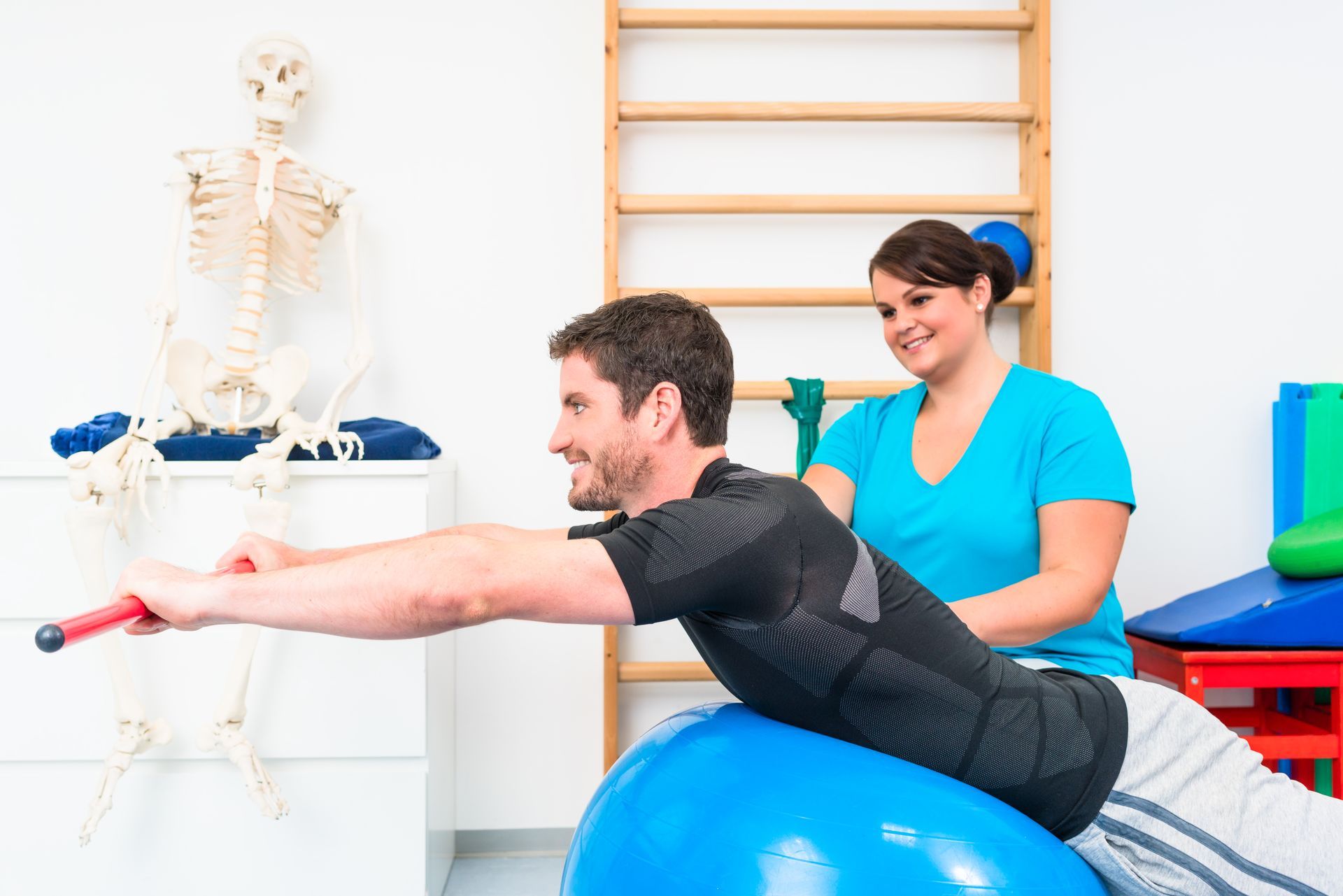 a man is doing exercises on a blue exercise ball with a skeleton in the background .