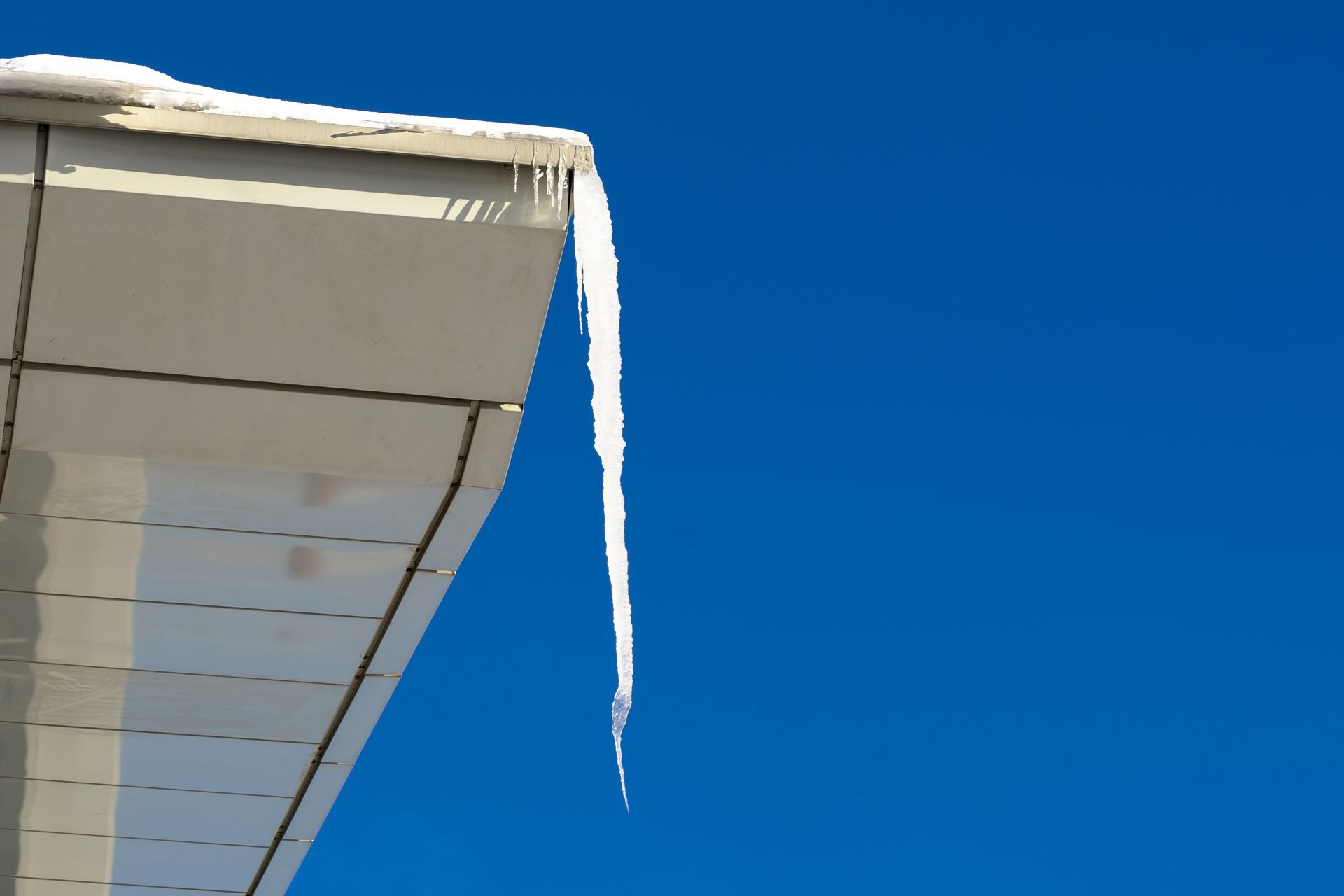 An icicle is hanging from the roof of a building