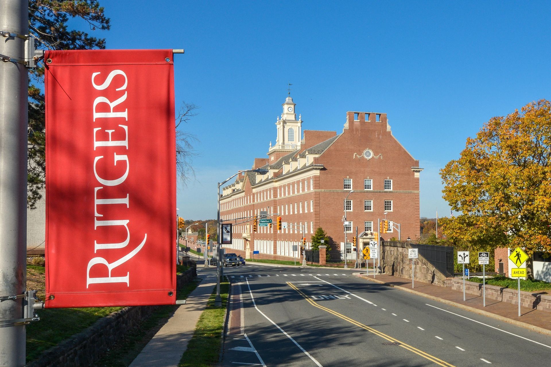 Rutgers University banner with brick building in the background, road, and blue sky. Visit our convenient downtown Brunswick location, where you're surrounded by shopping, dining, and local attractions. Start living better at The Brunswick apartments in downtown Brunswick, NJ. 